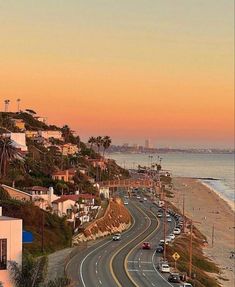 an empty road on the side of a beach with houses and palm trees in the background