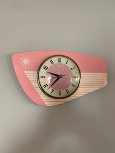 a pink clock mounted to the side of a wall