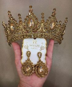 a hand holding a gold tiara and earrings