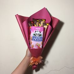 a hand holding a candy bar wrapped in pink paper