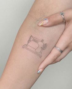 a woman's arm with a sewing machine tattoo on it