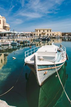 there is a boat that is docked in the water near some buildings and other boats