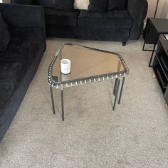 a living room with black couches and a coffee table in the middle on carpeted flooring