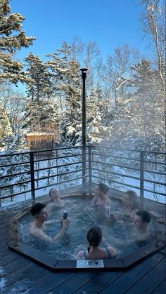 four people sitting in a hot tub with snow on the ground