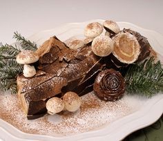 a piece of chocolate cake on a white plate covered in powdered sugar and sprinkles