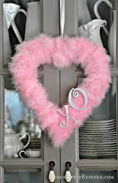 a pink heart shaped wreath hanging from the side of a door with text overlay that reads, feather heart valentine wreath