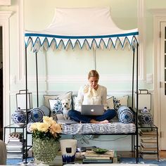 a woman sitting on a bed with a laptop in front of her and a dog