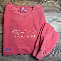 The Comfort Colors sweatshirt is the perfect choice to show your school spirit! This is designed for Sooner fans - a crimson sweatshirt with white thread. It's perfect for any gameday celebration with friends, family, or attending an event. This shirt comes in many colors and can be customized to your liking. Choose the color you'd like and what you would like embroidered on the sweatshirt.  Unless requested, embroidery will be in white. Be sure to look at other available t-shirts and sweatshirts by clicking here: https://www.etsy.com/shop/405Stitches?section_id=42561588. Two Tone Sweatshirt, Simple Embroidered Sweatshirt, Celebration With Friends, Custom Embroidered Sweatshirt, Embroidered Items, Boomer Sooner, Comfort Colors Sweatshirt, University Of Oklahoma, University Sweatshirts