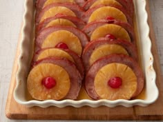 sliced up pineapples and ham in a white dish on a wooden cutting board