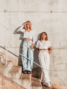 two women are standing on the stairs and one is holding her hand up to her face