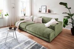 a living room with a green couch and white rugs on the wooden flooring