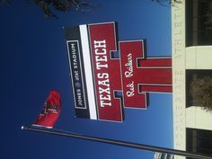 a large texas tech sign with a flag flying in the air next to it's name