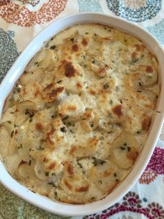 a casserole dish with potatoes and cheese in it on a colorful tablecloth