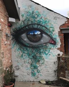 an eye painted on the side of a building with blue and green paint all over it