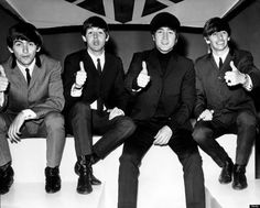 four men in suits and ties sitting on steps giving thumbs up