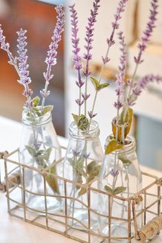 three glass bottles filled with flowers sitting on top of a table