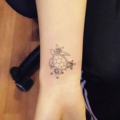 a small tattoo on the wrist of a woman's hand with flowers and a turtle