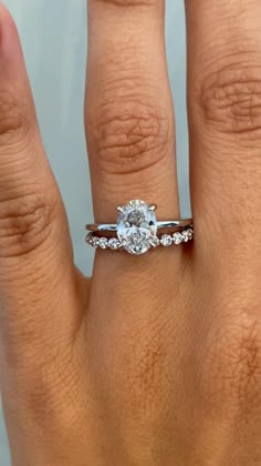 a woman's hand with a diamond ring on top of her finger and an engagement band