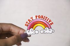 someone holding up a sticker that says stay positive with a rainbow in the background