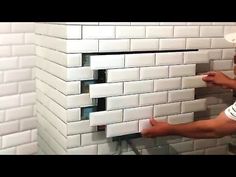 a man that is standing in front of a brick wall with some tiles on it