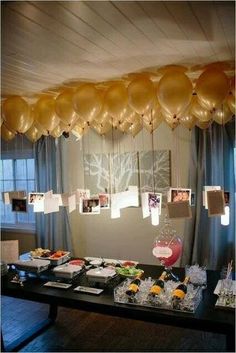 balloons are hanging from the ceiling above a buffet table with food and drinks on it