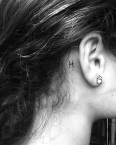 a woman's ear has a small cross tattoo on it