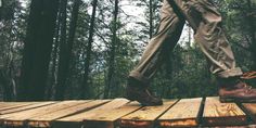 a person walking across a wooden platform in the woods