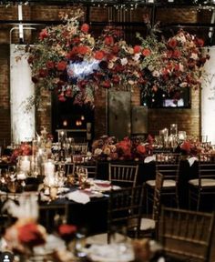 a room filled with lots of tables and chairs covered in floral center piece hanging from the ceiling