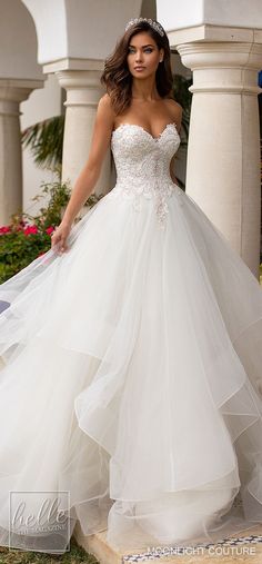 a woman in a white wedding dress is standing on the steps outside with her arms behind her back