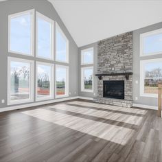 an empty living room with wood floors and large windows