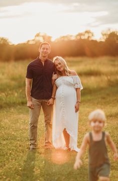 a pregnant woman standing next to a man in a field