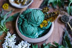 a bowl filled with green ice cream next to flowers