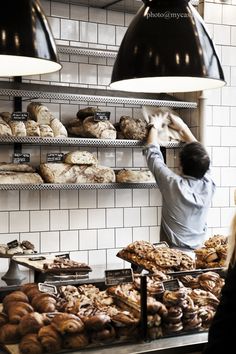 a man working in a bakery with lots of breads and pastries on shelves