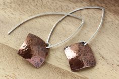 Hand formed sterling silver open hoops in an almond shape with dangling hammered copper squares, in a diamond shape. These light weight copper earrings have a light patina that brings out an earthy warm quality. Modern and a bit rustic! These earring are 1 3/4 inches (4.5 cm) long in the front, the back hangs a bit longer.  The copper square is 5/8 x 5/8 inches (16 mm) All earrings come with clear earring stoppers. All of my designs are created by me, including all the metal components like ear Handmade Modern Copper Jewelry, Modern Handmade Copper Jewelry, Artisan Rose Gold Sterling Silver Jewelry, Modern Copper Jewelry For Pierced Ears, Everyday Copper Drop Earrings, Minimalist Hammered Copper Jewelry, Artisan Hammered Rose Gold Jewelry, Artisan Rose Gold Hammered Jewelry, Modern Nickel-free Copper Jewelry