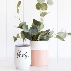 two white and pink vases with plants in them