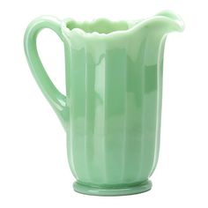 a green glass pitcher sitting on top of a white table