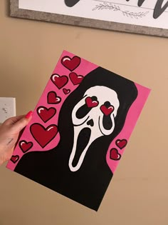 a person holding up a piece of art with hearts in the shape of a skull