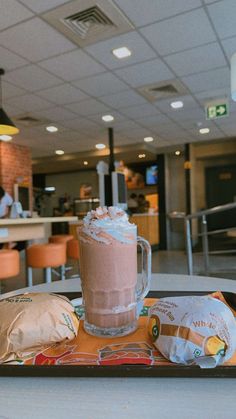 there is a tray with food and drink on it in front of a table at a restaurant