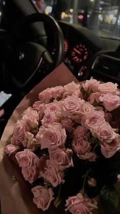 a bouquet of pink roses sitting on top of a table in front of a car