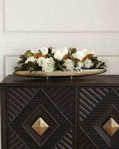 a black cabinet with white flowers and greenery on top