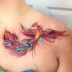 a colorful bird tattoo on the back of a woman's upper arm and shoulder