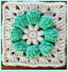 a crocheted square with green and white flowers