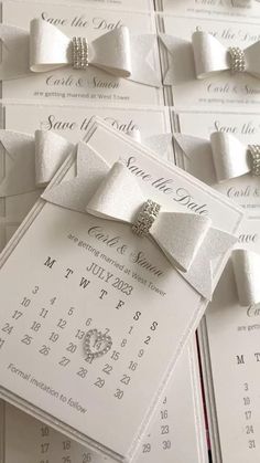 the wedding stationery is laid out on top of each other with bows and brooches