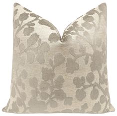 a beige and white floral pillow on a white background