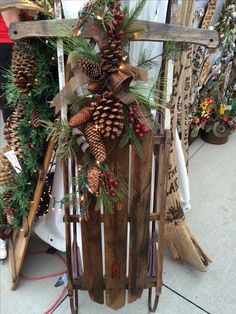 a sled decorated with pine cones, evergreens and other holiday decorations is displayed