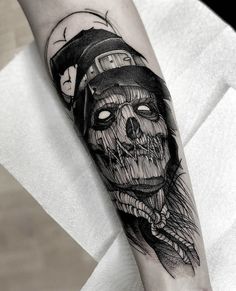 a skull with a hat and bow tie tattoo on the arm, done by an artist