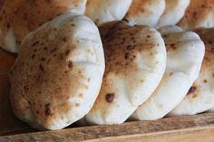 some breads are sitting on a wooden tray and ready to be eaten by someone