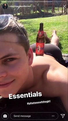 a man with no shirt on laying in the grass next to two bottles of beer