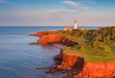 an aerial view of a lighthouse on the edge of a cliff overlooking the ocean and trees