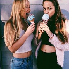 two women standing next to each other eating ice cream cones